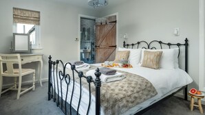Een slaapkamer met een bed, nachtkastje, stoel en een klein krukje.