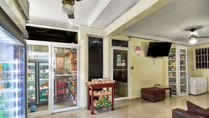 En rummelig lobby med et køleskab fyldt med drikkevarer, et udvalg af snacks og et fjernsyn monteret på væggen.