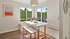 Una cocina moderna con una mesa blanca, asientos tipo banco y una lámpara colgante.