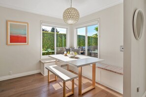 Une cuisine moderne avec une table blanche, des bancs et un luminaire suspendu.