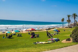 Une plage avec des gens, des parasols et des planches de surf.