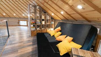 Cozy attic retreat with a sloped ceiling and shelving, featuring a comfortable sofa and wooden floor.