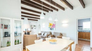 A modern living room with a white dining table, beige sofas, and a kitchen in the background. - 3 Bedroom Villa, Private Pool, Close to the beach, Binibeca (Binibeca)