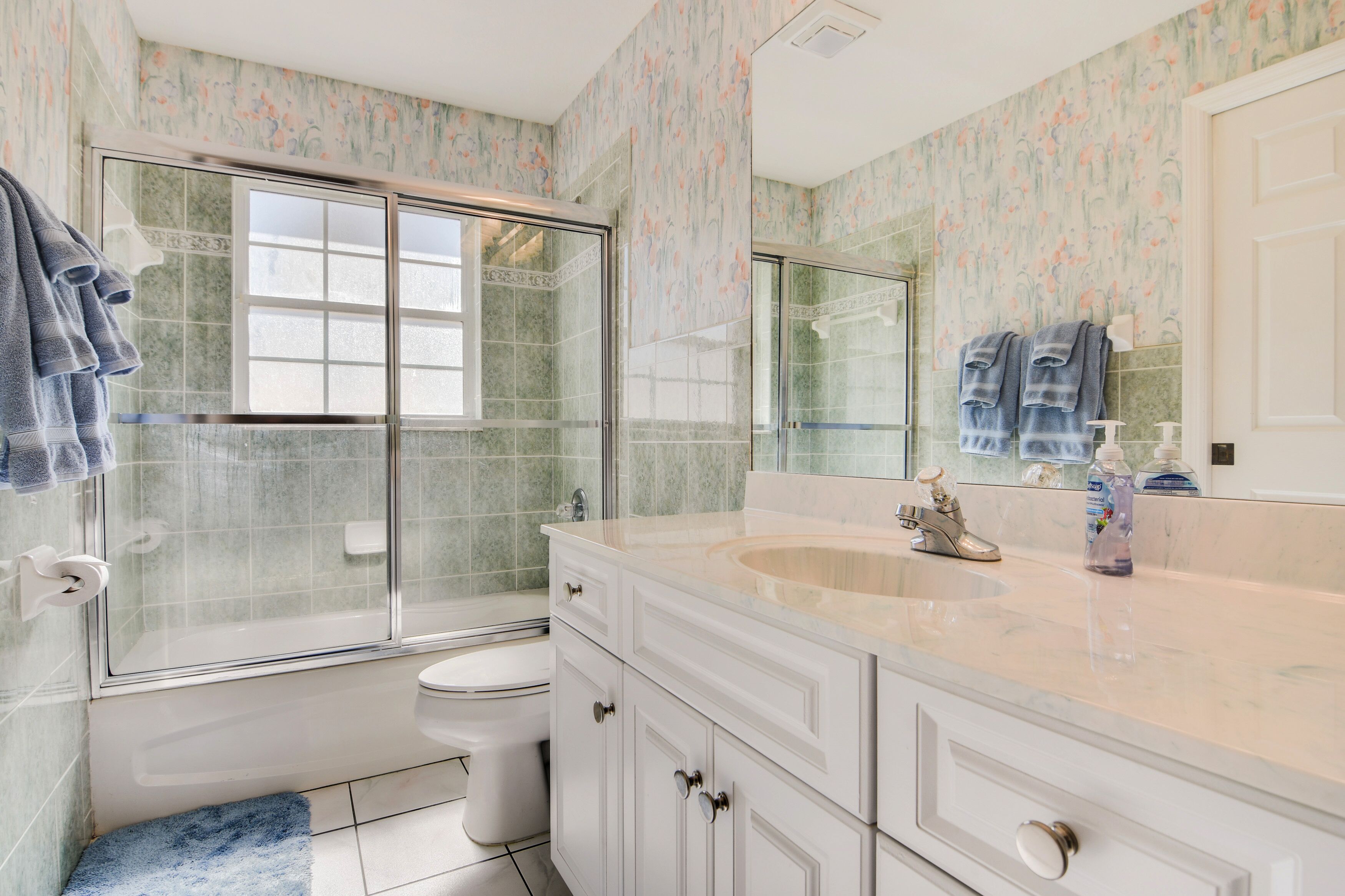 Une salle de bain avec une douche à parois de verre, des toilettes et un meuble-lavabo avec un évier et un miroir.