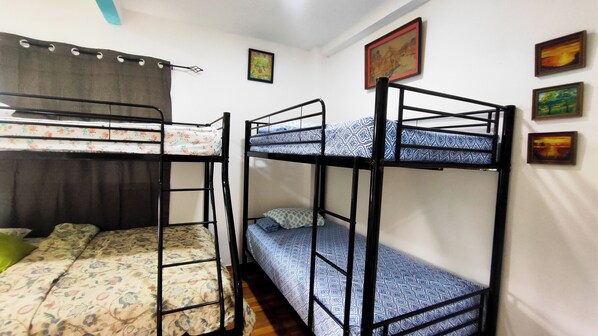 A dormitory room with bunk beds, a curtain, and several framed pictures on the wall. - Hostal Las Catalinas Ecológicas (El Valle de Anton)