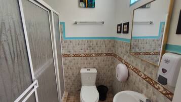 Un baño pequeño con inodoro, bidé y secamanos.