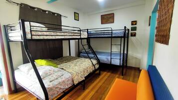 A bunk bed room with a wooden floor, a small orange chair, and a blue wall decoration.