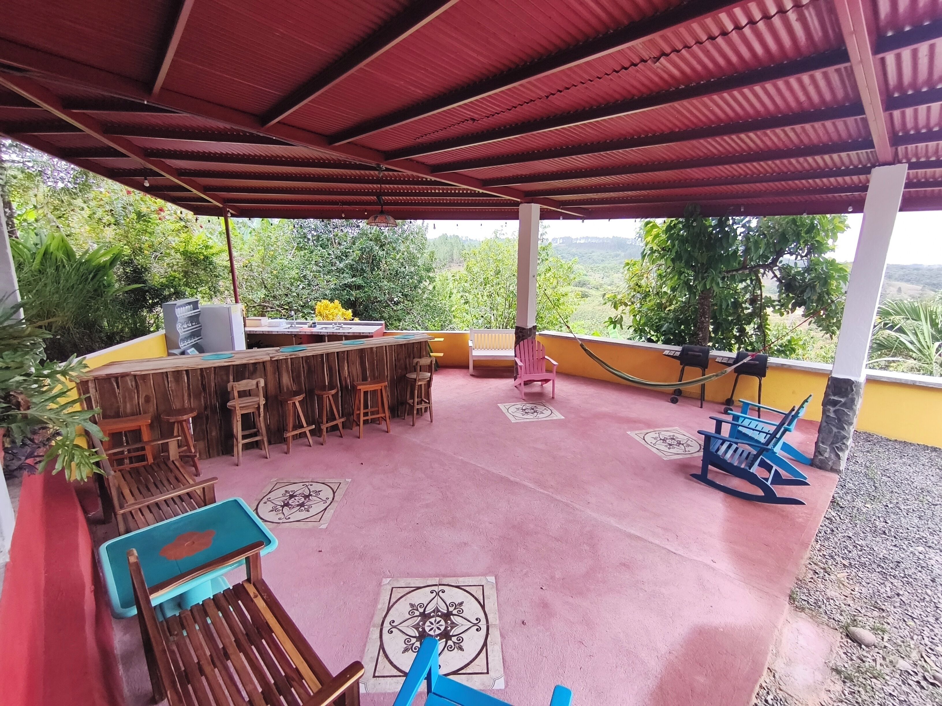 An outdoor patio with a wooden bar, seating, and a view of the landscape.