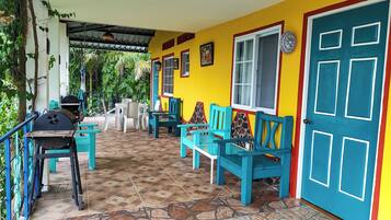 Un espace patio avec des chaises et des tables turquoise, un barbecue et une porte bleue.