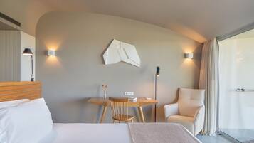 Una habitación de hotel moderna con cama, escritorio, silla y un amplio ventanal.