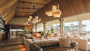 Un vaste espace de détente moderne, doté de canapés en cuir, d’un bar et de grandes fenêtres offrant une vue sur l’extérieur.