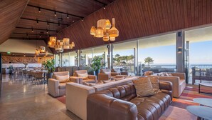 Un hall d’entrée spacieux, doté de canapés en cuir, d’un coin repas et de grandes fenêtres offrant une vue sur la mer.