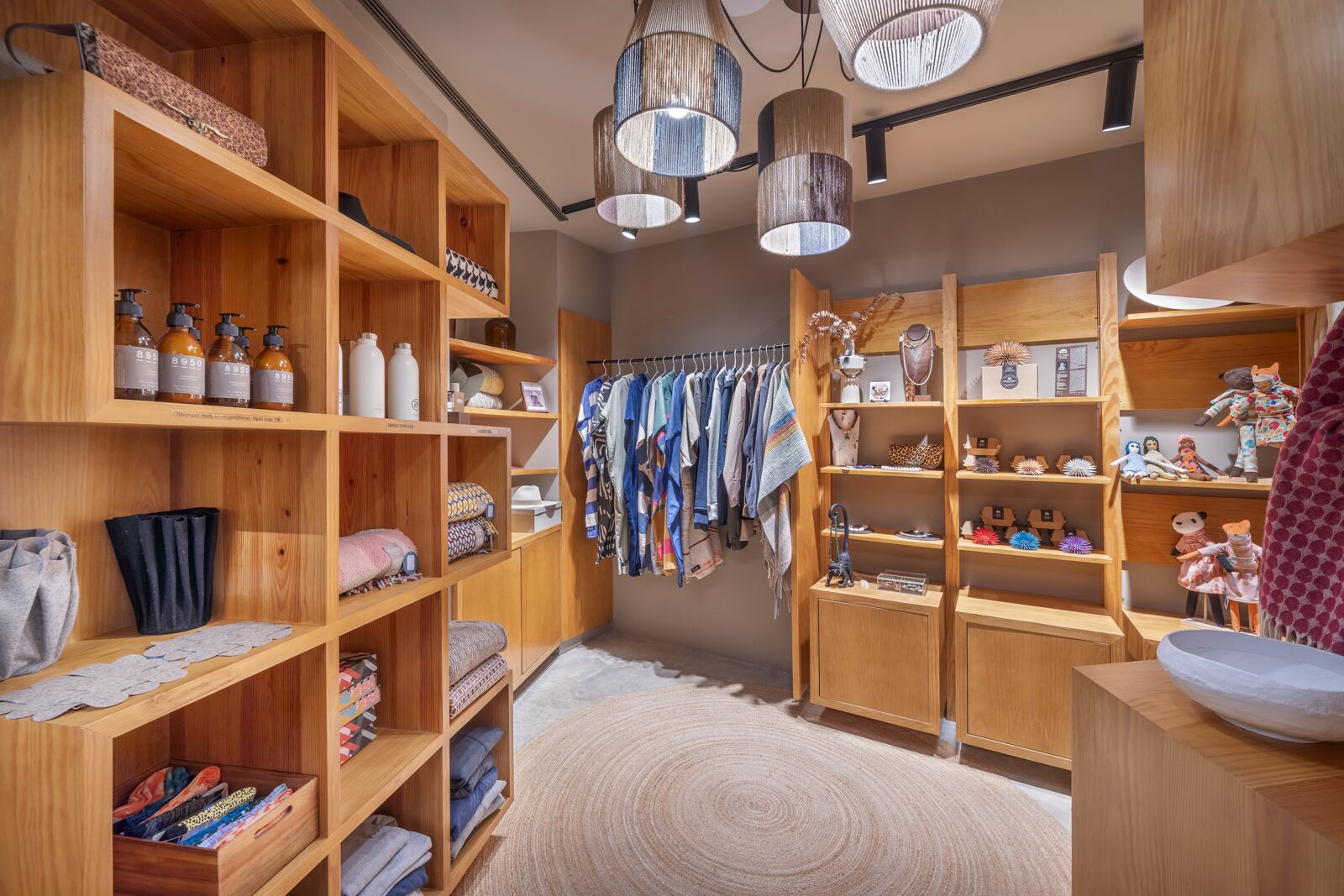 Une pièce de rangement bien organisée, avec des étagères en bois, des vêtements suspendus et divers objets.
