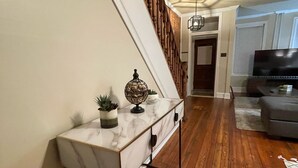 A living room with a marble console table, wooden flooring, a staircase, and a television. - Home Sweet Home @Trolley Square!<br><br>https://goo.gl/maps/f1XX68qiTRCU7eFk7<br> (Wilmington)