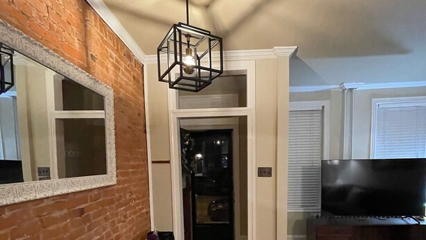 A modern living room with a brick wall, a large TV, and a wooden floor. - Home Sweet Home @Trolley Square!<br><br>https://goo.gl/maps/f1XX68qiTRCU7eFk7<br> (Wilmington)