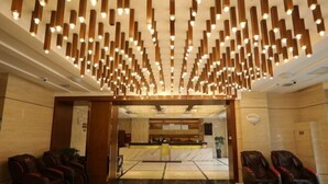 A hotel lobby with massage chairs, a reception desk, and a modern ceiling design. - Tonghe Hotel (Shimian)