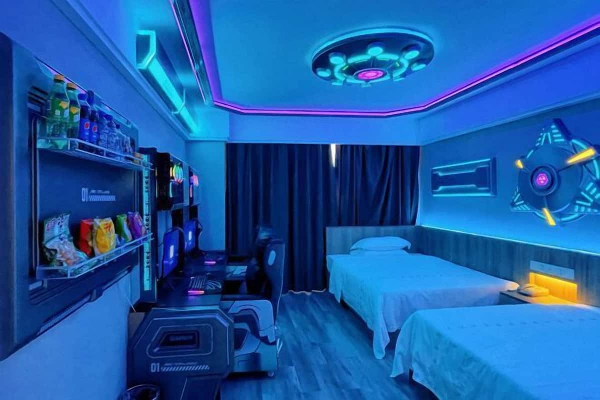 A modern hotel room with a workout area, a bed, and a wall-mounted control panel.