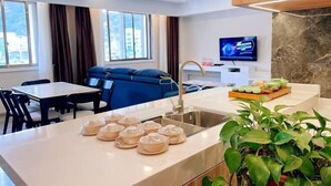 A modern hotel room with a dining area, a TV, a sink, and a plant. - Tonghe Hotel (Shimian)