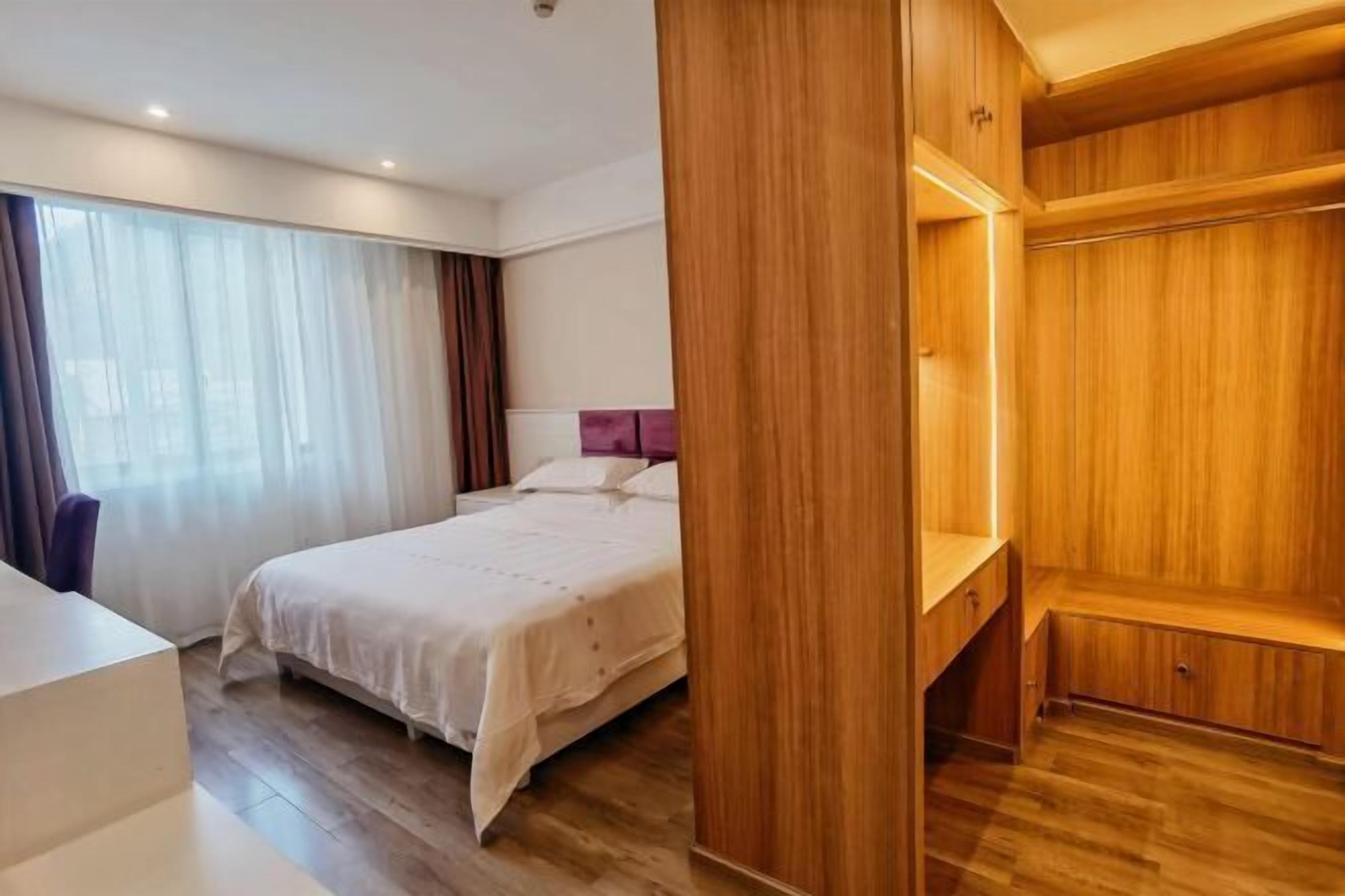 A hotel room with a bed, a desk, and a wooden wardrobe.