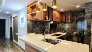 A modern kitchen with a marble backsplash, wooden cabinets, and pendant lighting. - Tonghe Hotel (Shimian)