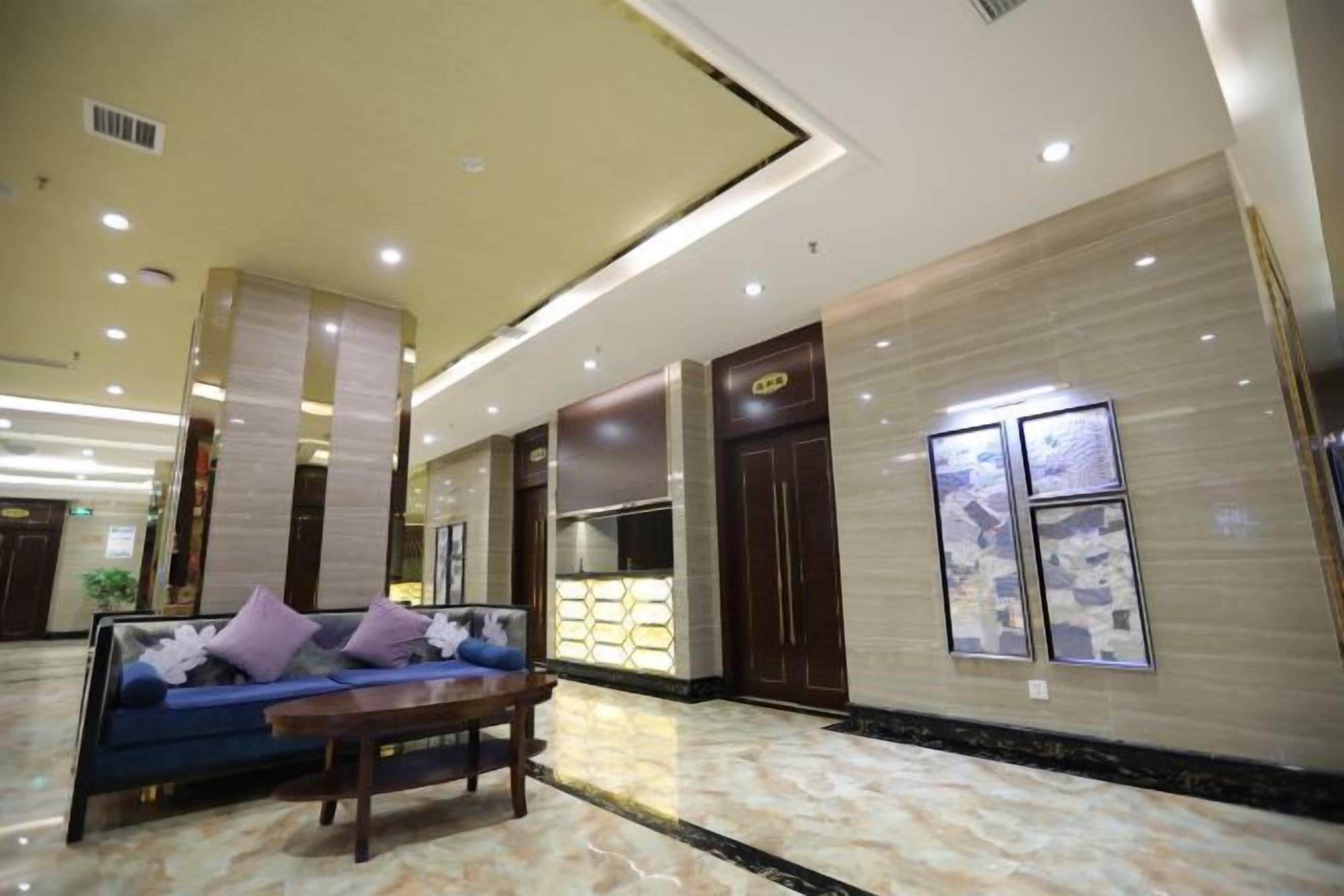 A hotel lobby with a sofa, a coffee table, a reception desk, and a large window.