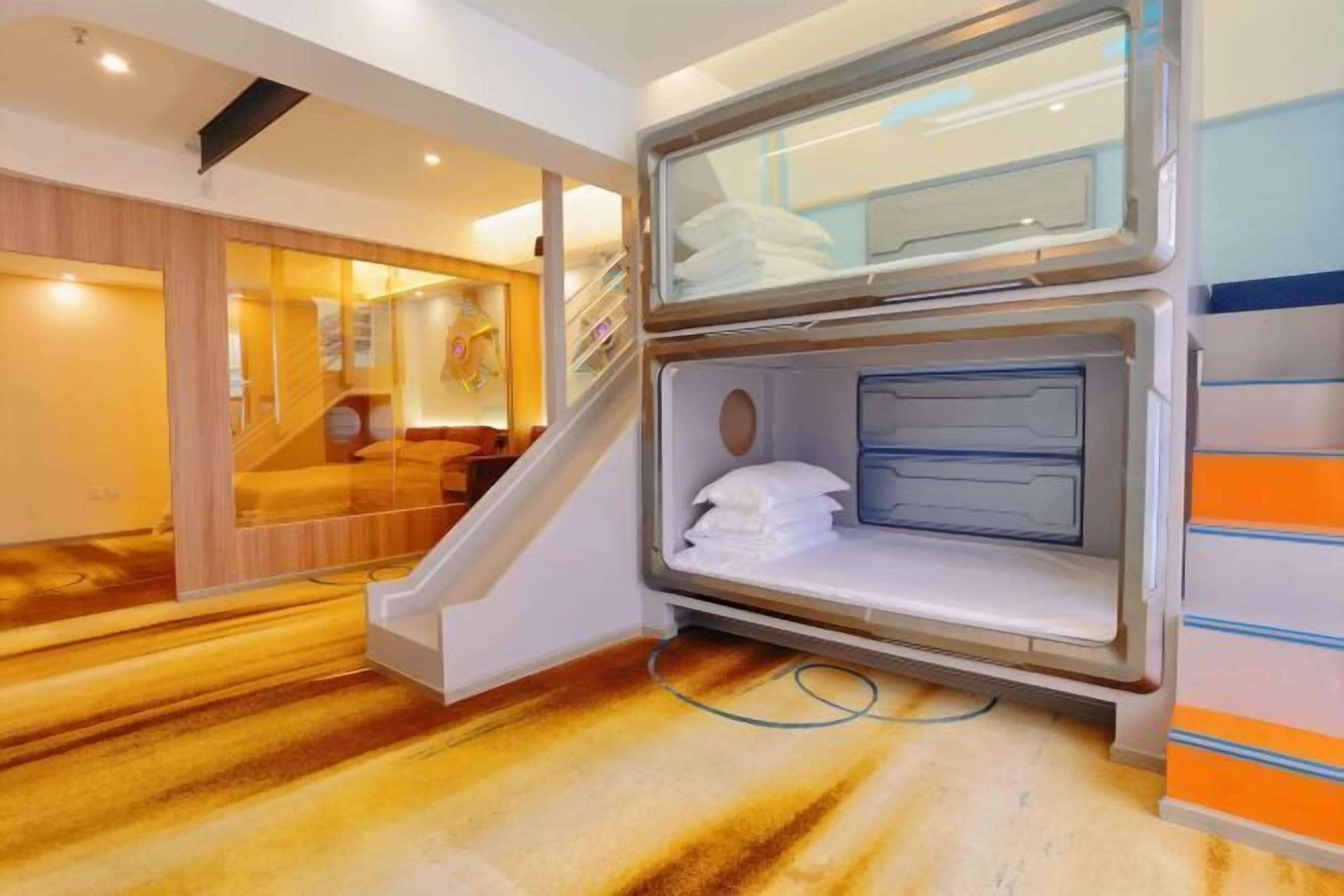 A hotel room with a built-in shower, a wooden floor, and a staircase leading to another room.
