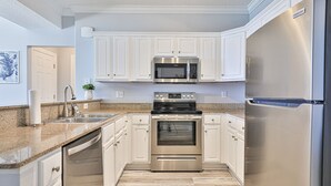 A modern kitchen with white cabinets, stainless steel appliances, granite countertops, and a dishwasher.