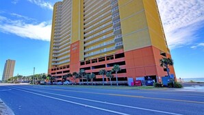 A multi-story hotel with a yellow and orange facade, multiple balconies, and a parking garage.