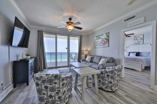 A spacious living area with a ceiling fan, a sofa, a coffee table, and patterned armchairs.