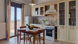 A modern kitchen with a dining area, featuring a stove, cabinets, and a view through the glass doors. - Villaki studio geust house,Private pool (Maroulas)