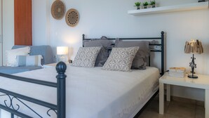 A neatly arranged bedroom with a bed, bedside tables, and decorative wall hangings. - Villaki studio geust house,Private pool (Maroulas)