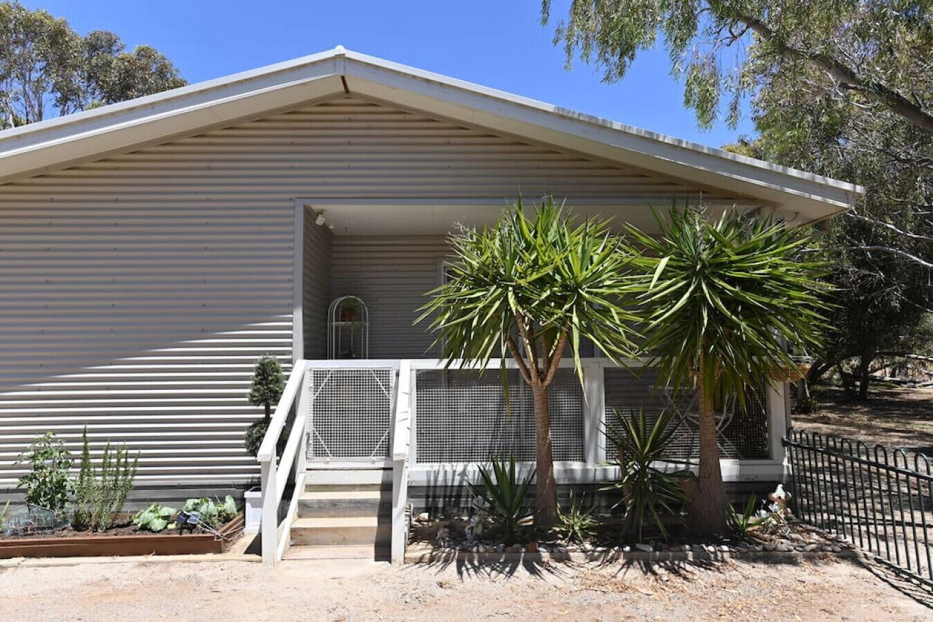 A single-story building with a sloped roof, a covered porch, and a small staircase leading to a door.