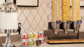 A breakfast bar with a coffee machine, cereal dispensers, and Quaker Oats cereal boxes.