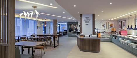A modern cafe with wooden furniture, a central counter, and artwork on the walls.