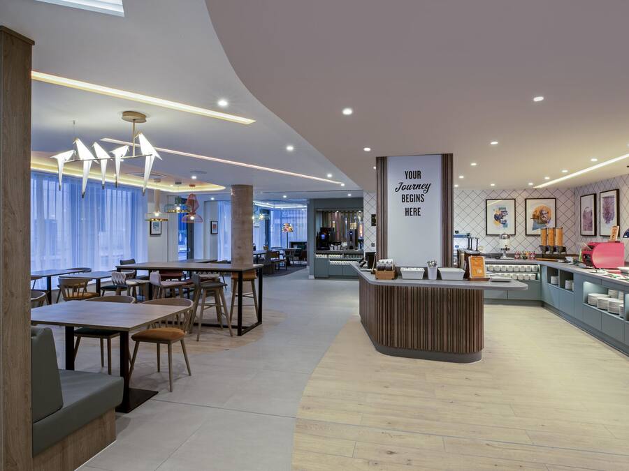 A modern cafe with wooden furniture, a central counter, and artwork on the walls.