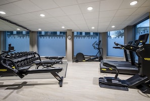 Un gimnasio con equipo de ejercicio, un reloj y una ventana con vistas.