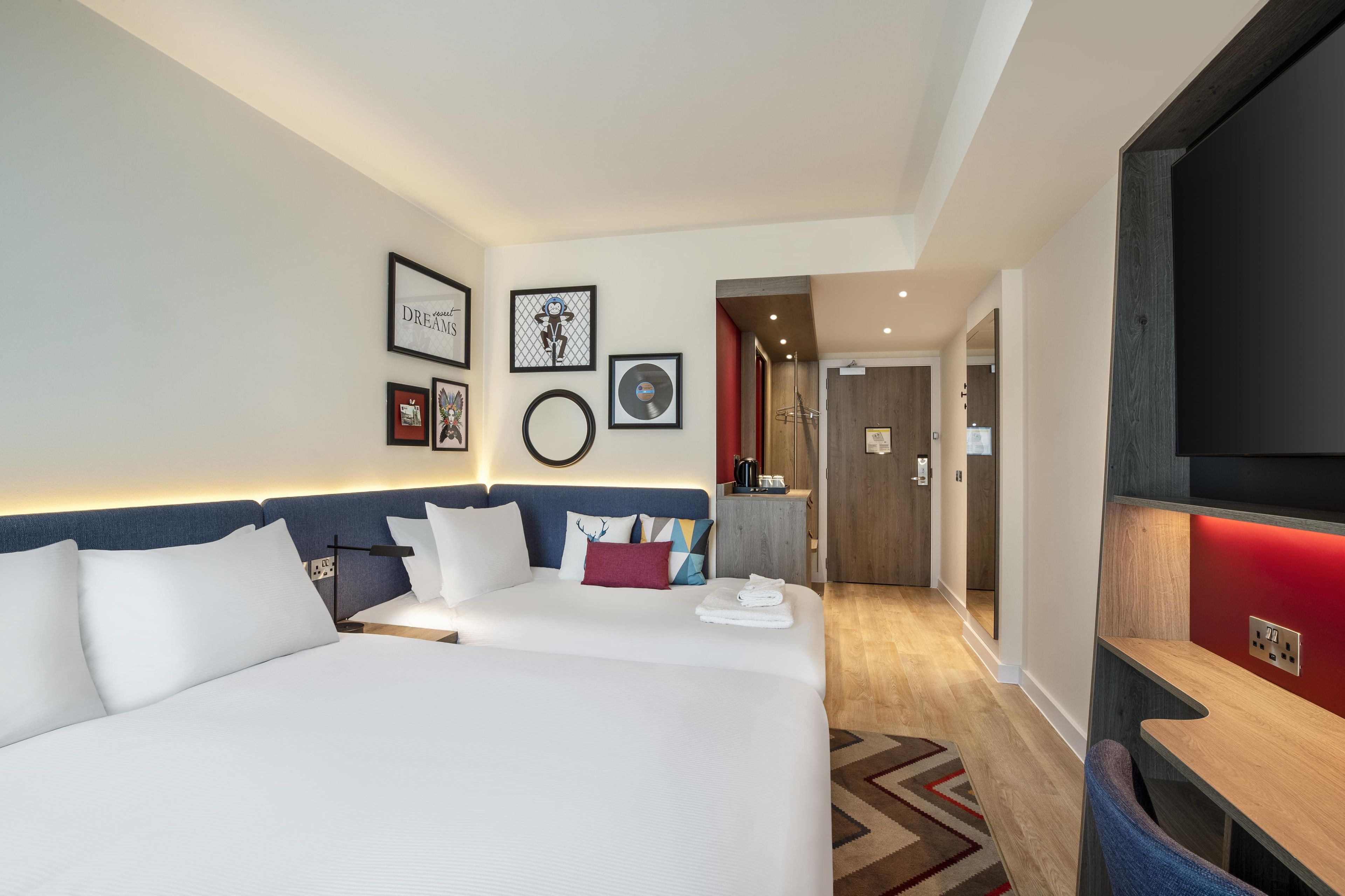 Una camera d'albergo con un letto grande, una televisione e un parete decorata con quadri.