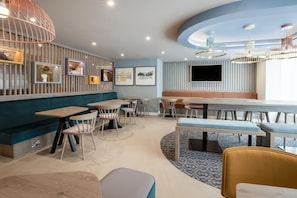 Un interior de restaurante moderno con cabinas, mesas y una zona de bar.