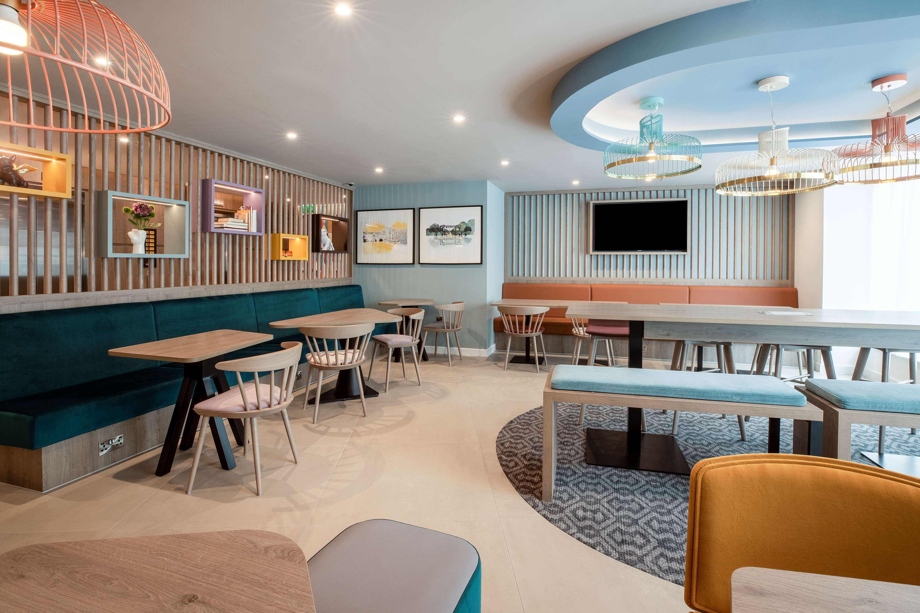 Ein modernes Restaurant mit gewölbter Decke, Holzvertäfelung und verschiedenen Sitzmöglichkeiten, darunter Sitzecken und Tische.