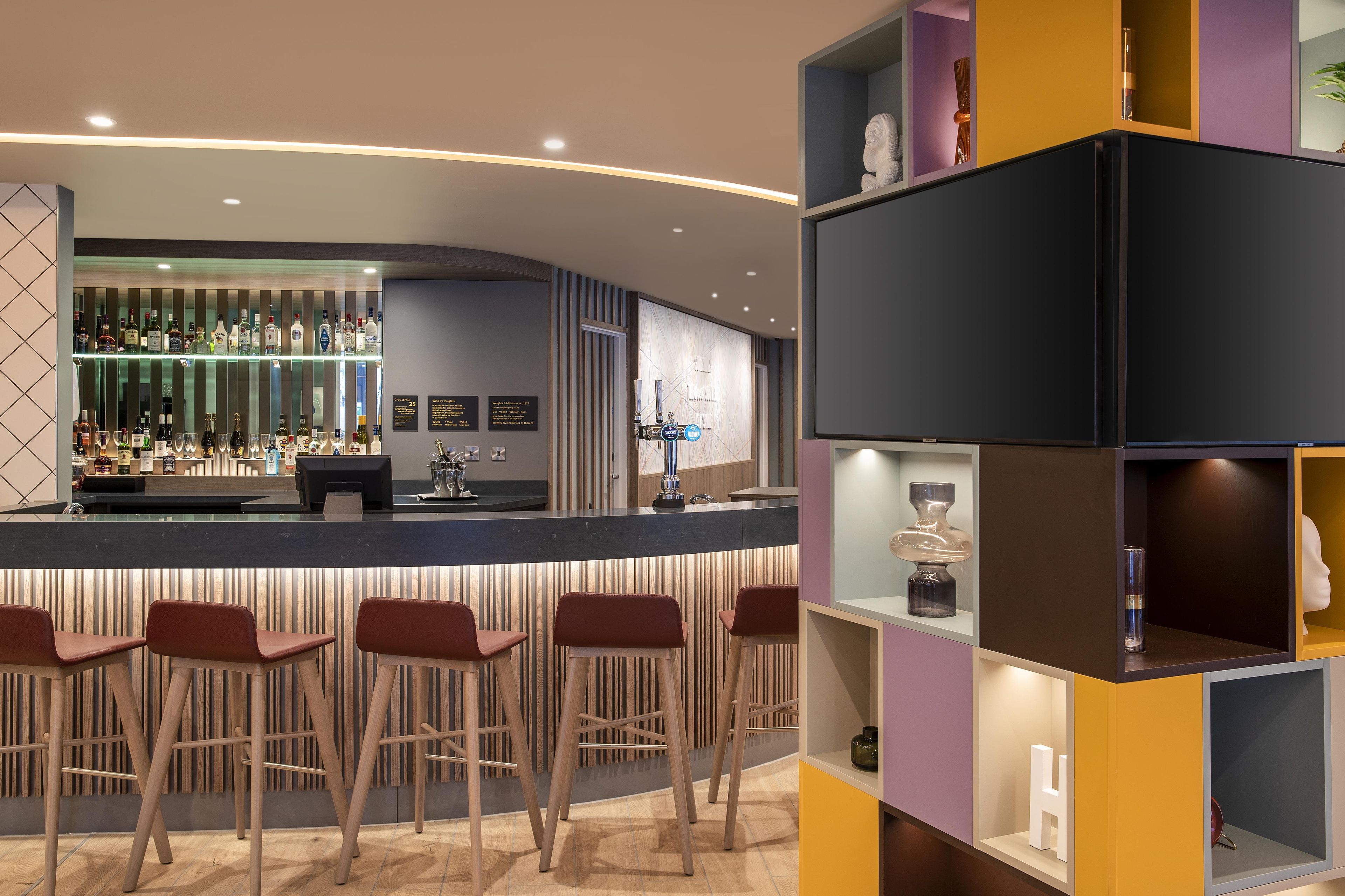 Una zona de bar con taburetes, una barra y una variedad de botellas.