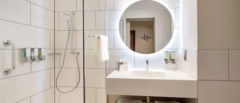 A modern bathroom with a walk-in shower, a large mirror, and a vanity with a sink.