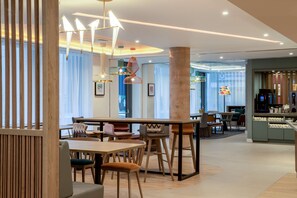 Um restaurante moderno com mobiliário de madeira, luminárias pendentes e um espaço de bar.