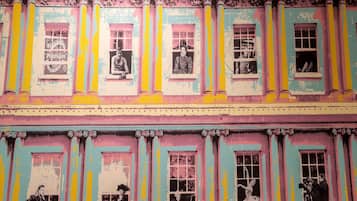 A building facade with multiple windows, some with posters and mannequins.