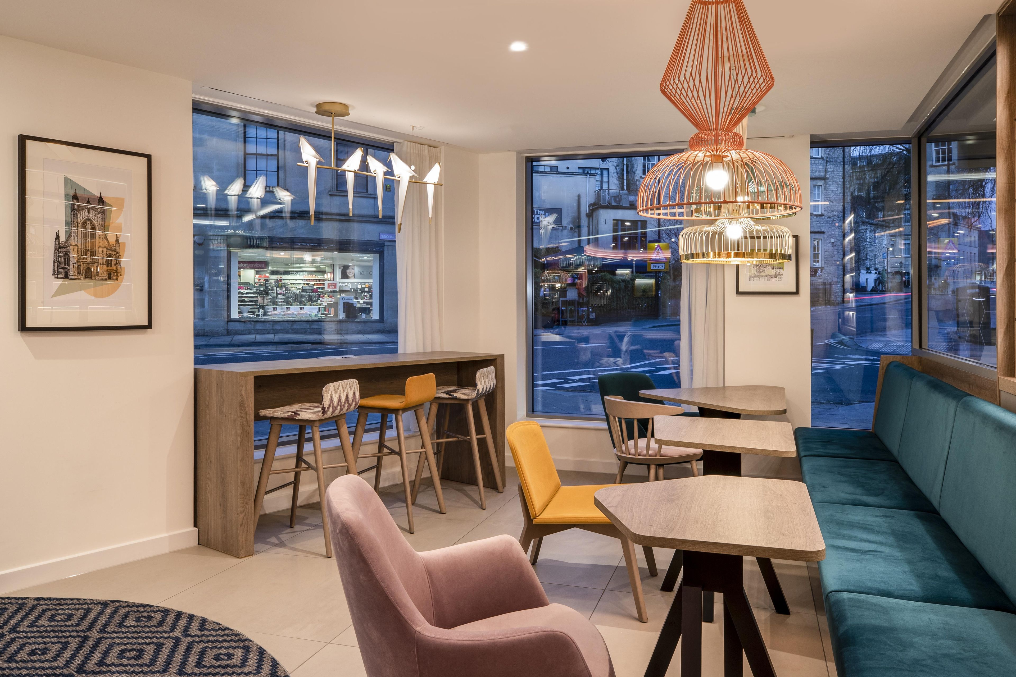A modern interior with a bar area, seating, and large windows offering city views.