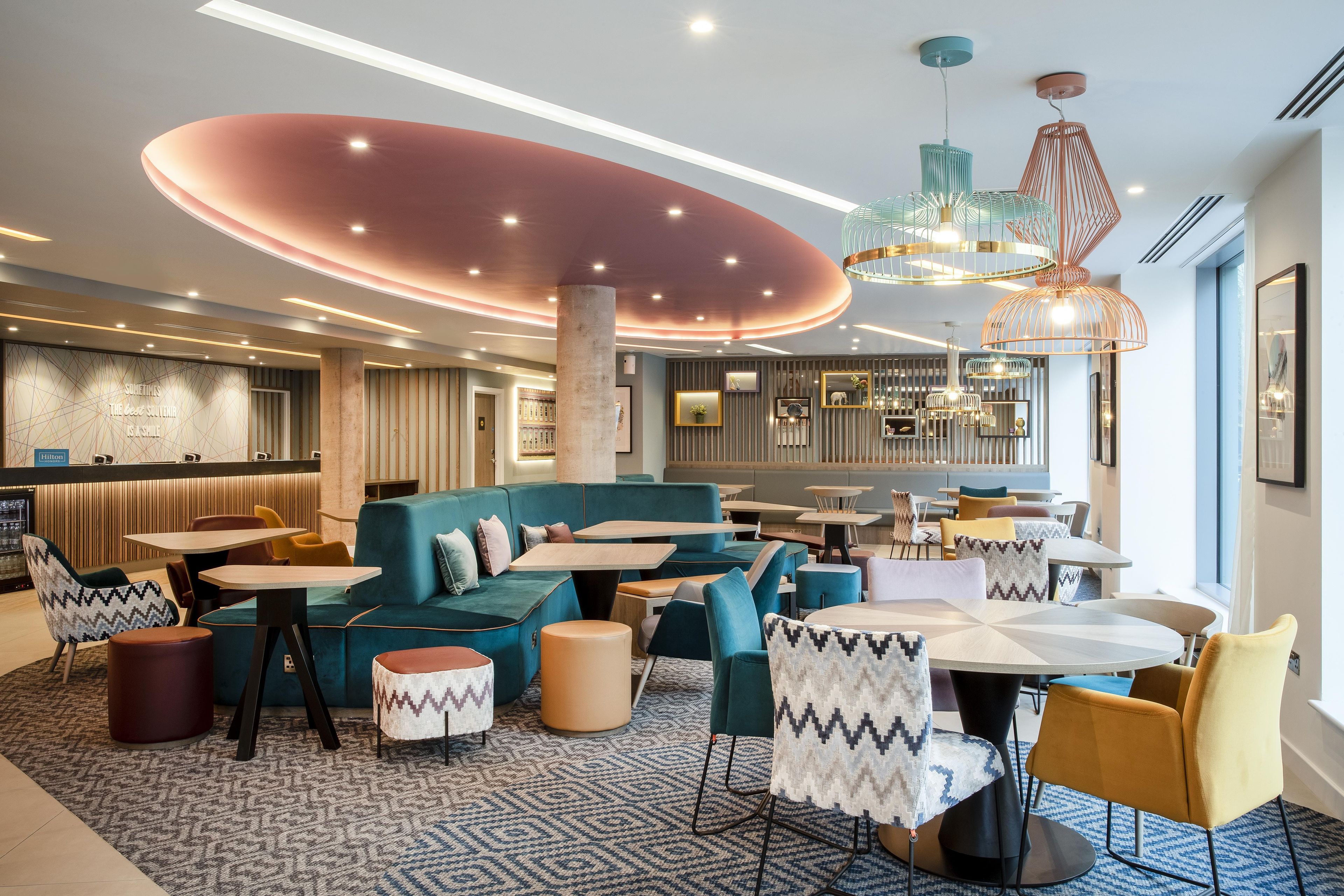 Un moderno vestíbulo de hotel con un área de descanso, mesas y un bar.