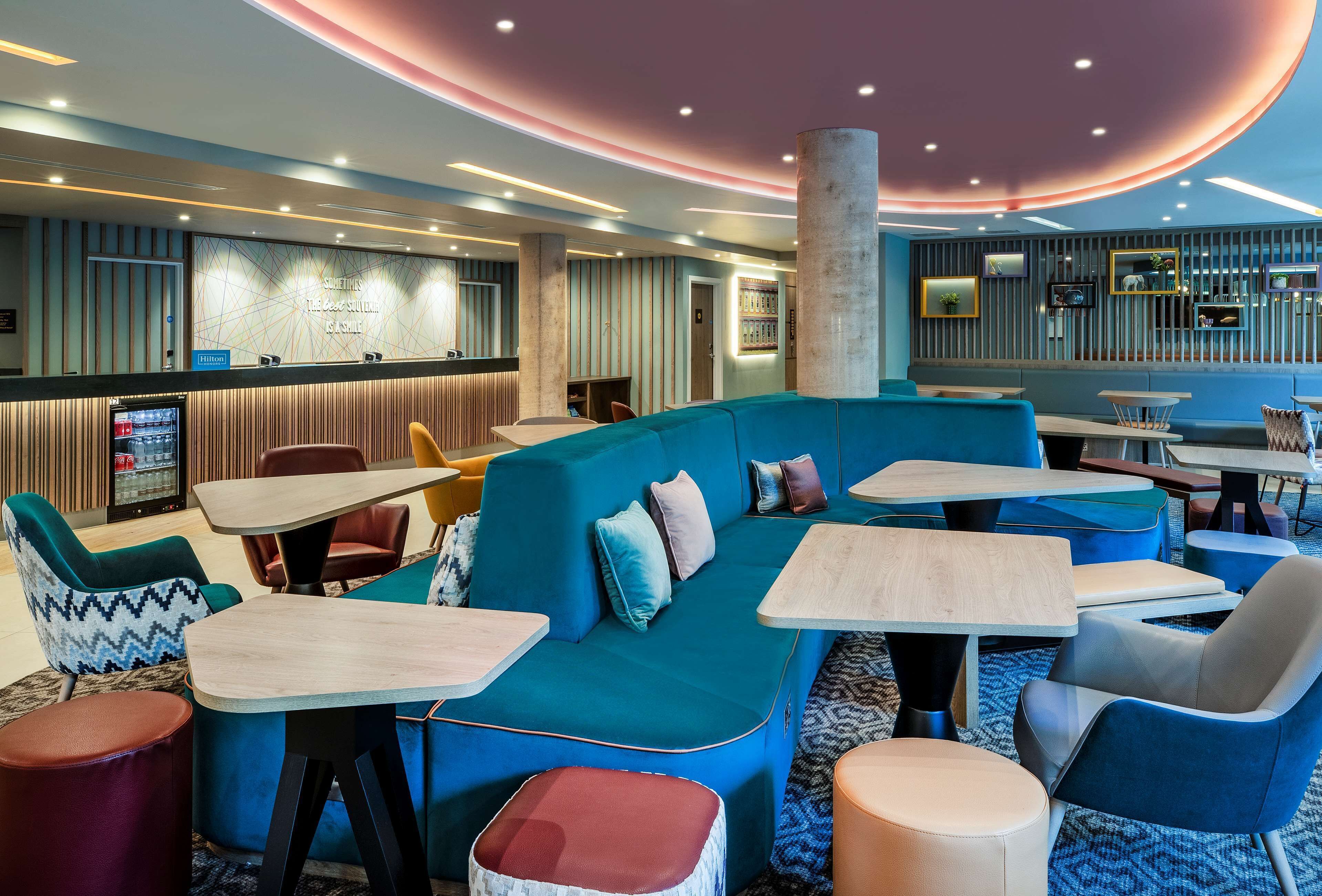 A modern hotel lobby with a curved ceiling, seating areas, and a reception desk.