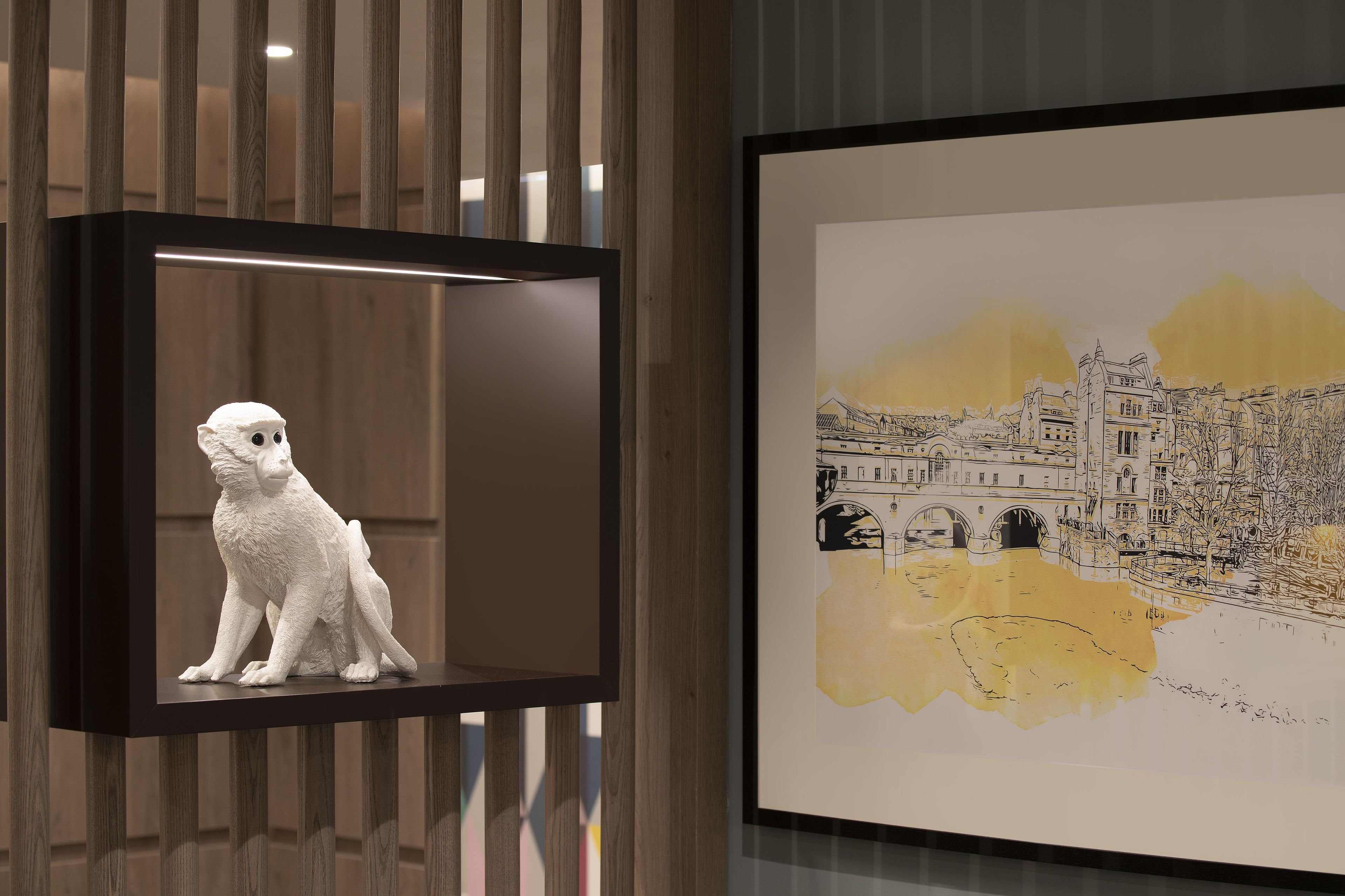 A framed artwork with a cityscape and a white sculpture of a monkey.