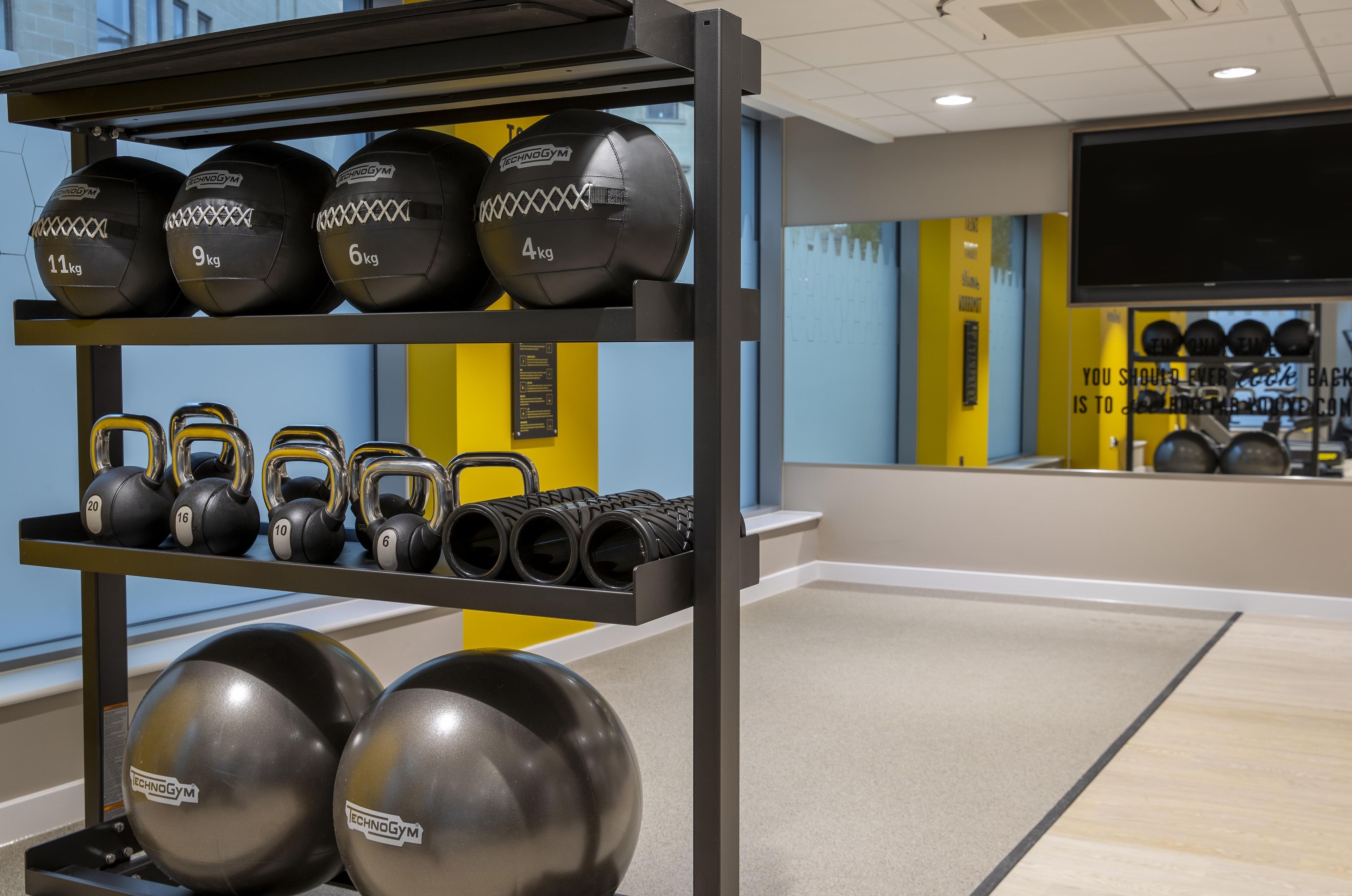 A gym with weightlifting equipment including kettlebells and medicine balls.