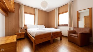 Una camera da letto con rivestimenti in legno, un letto, comodini, una sedia e uno specchio grande.