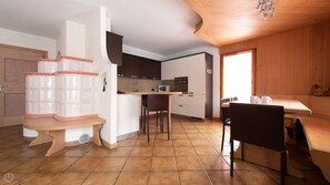 A modern kitchen with a central island, a dining area with a wooden table and chairs, and a wooden ceiling.